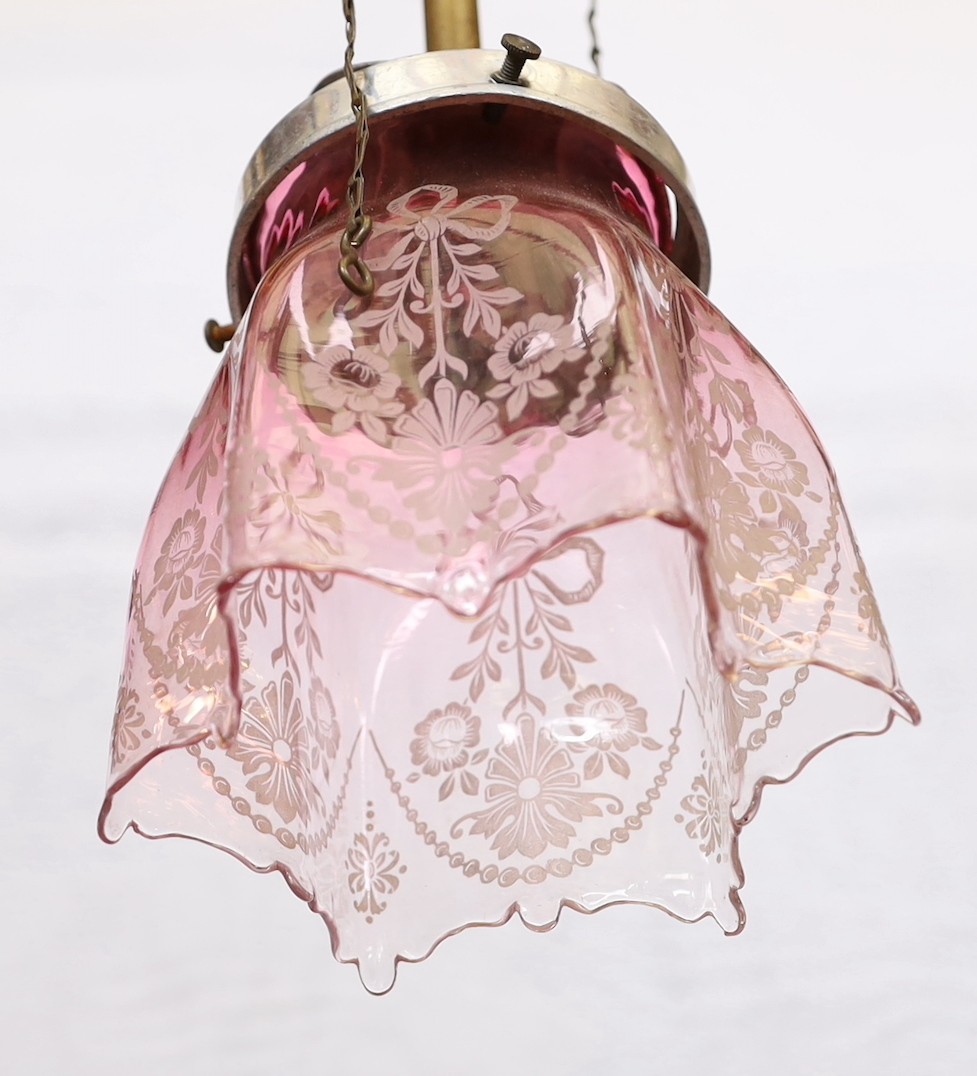 An early 20th century English brass gasolier light fitting, converted to electricity, with pink tinted etched glass shade, height 50cm